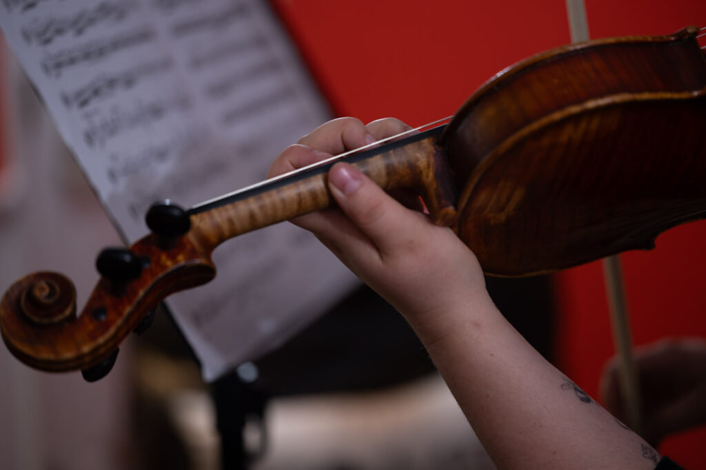 violinist holding a violin in front of sheet music