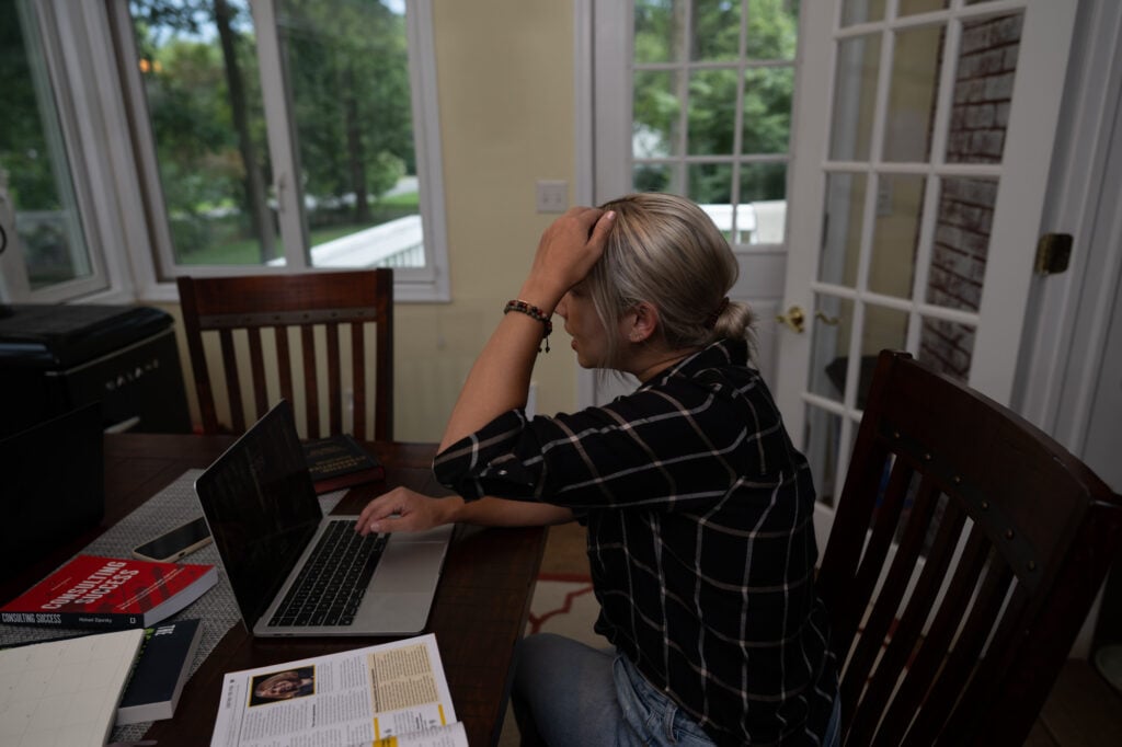 Woman in an office looking frustrated with her hand on her head