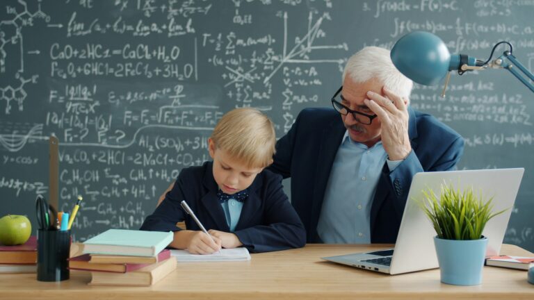 Old-style classroom with an elderly male teacher tutoring a child in math.