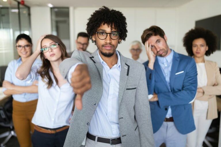 disgruntled group of employees giving a thumbs down and looking exasperated to demonstrate the cost of toxic leadership