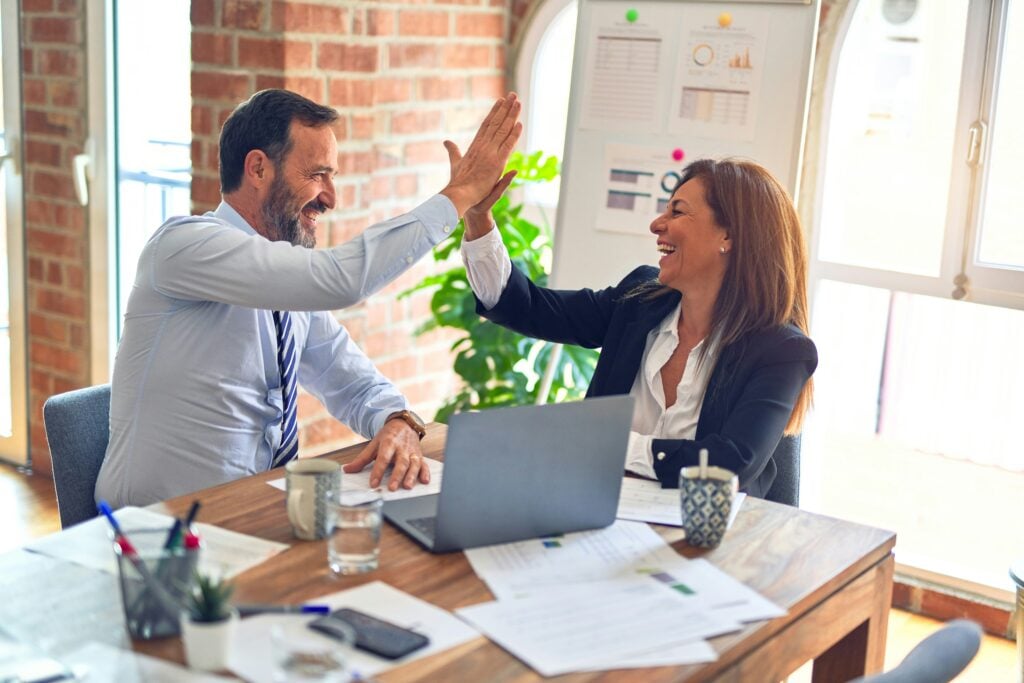 business professionals high-fiving at a conference desk