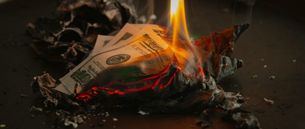 image of money burning to demonstrate revenue loss from a toxic leader's management and the effects of their toxicity