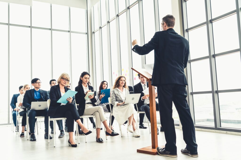 professionals in a group leadership coaching session led by a man at a podium