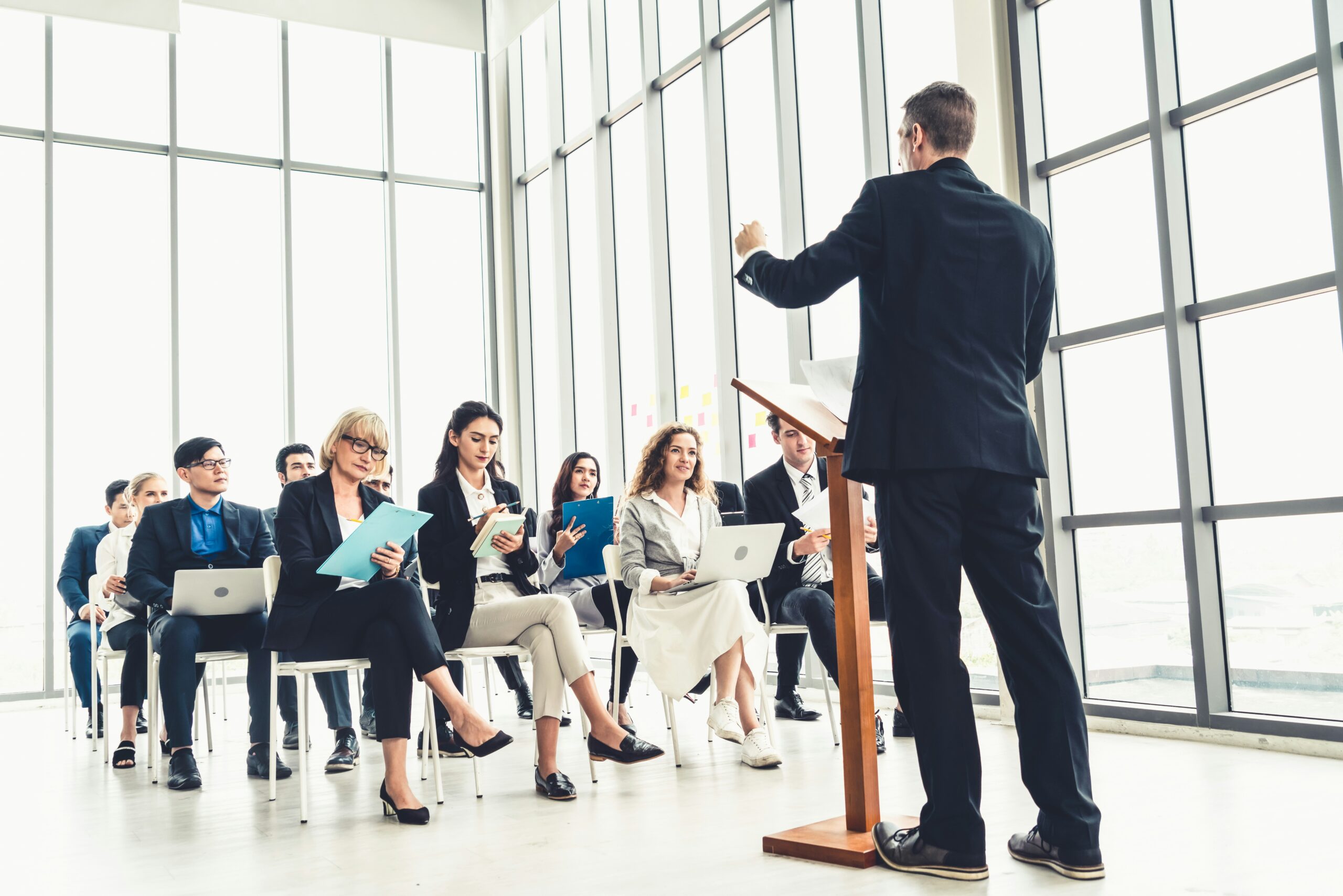 professionals in a group leadership coaching session led by a man at a podium