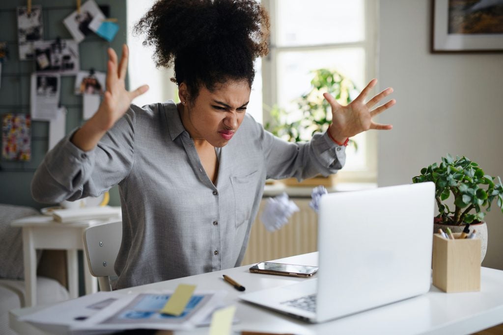 woman frustrated at her desk and holding up her hands to express discontent from a toxic leader