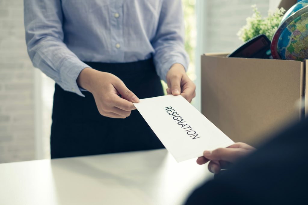 image of a person handing a manager a resignation letter to demonstrate the cost of toxic leadership on staff retention